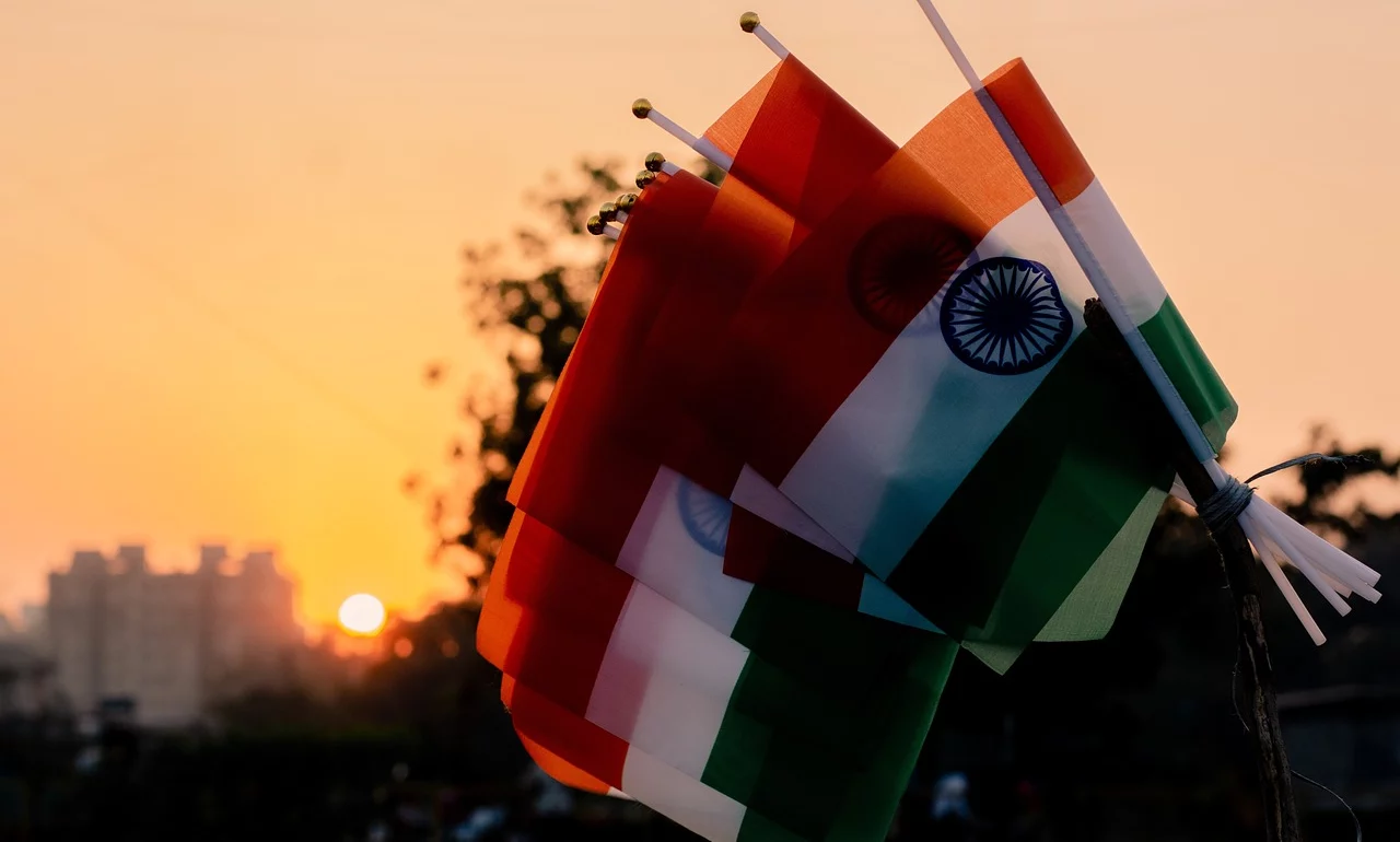 A series of Indian flags dipped with the sun setting behind them.