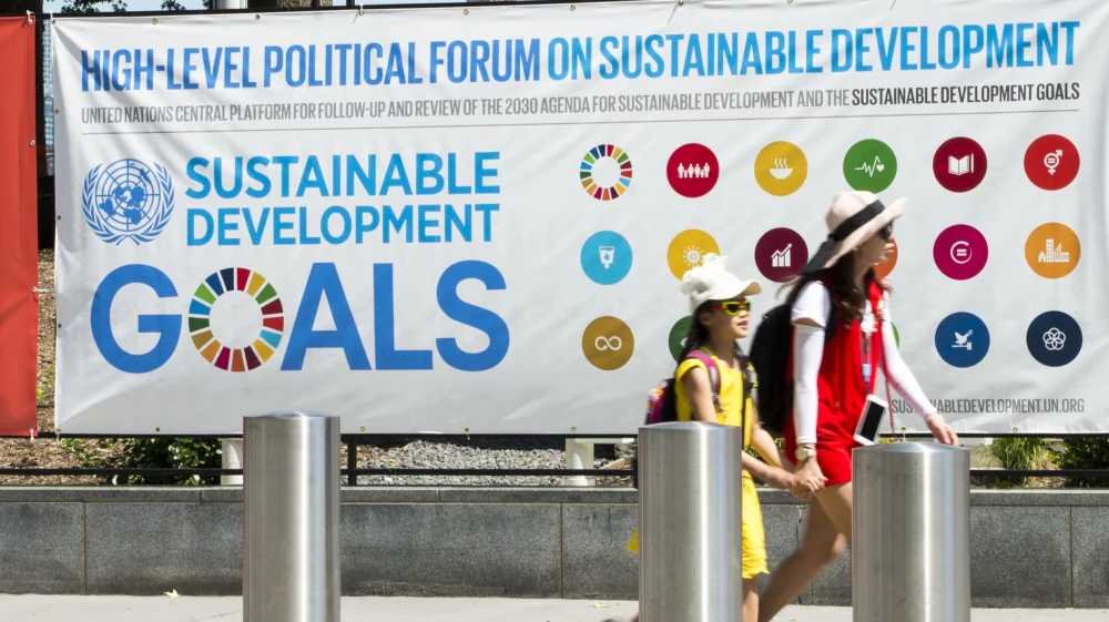 Woman and girl walking in front of a banner outlining the UN sustainable development goals