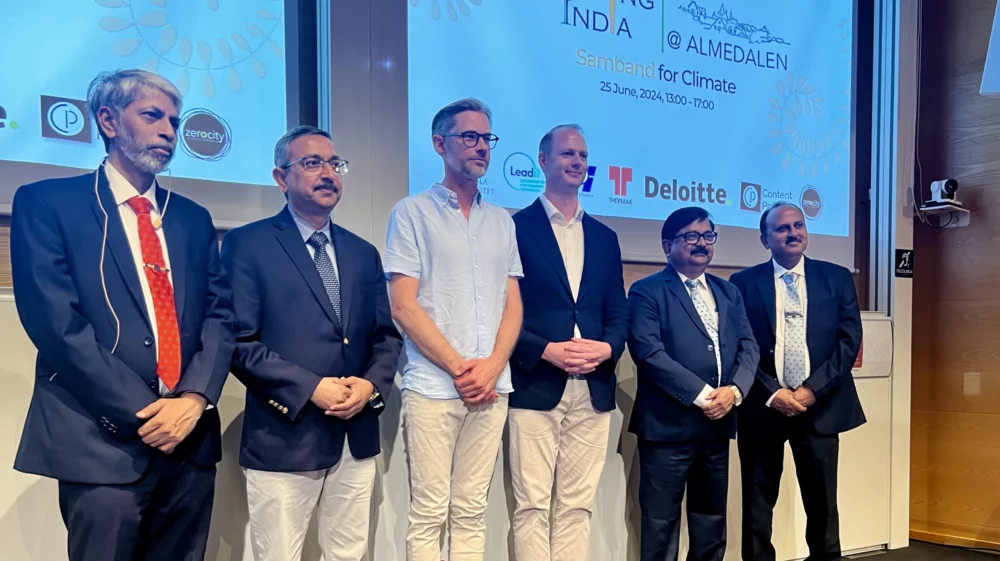 Group photo of six men on stage at the ‘Engaging India at Almedalen’ event, with logos of sponsoring organizations displayed on the screen behind them. The individuals, including the Indian Ambassador to Sweden and executives from SAIL and Cemvision, are dressed in business attire.