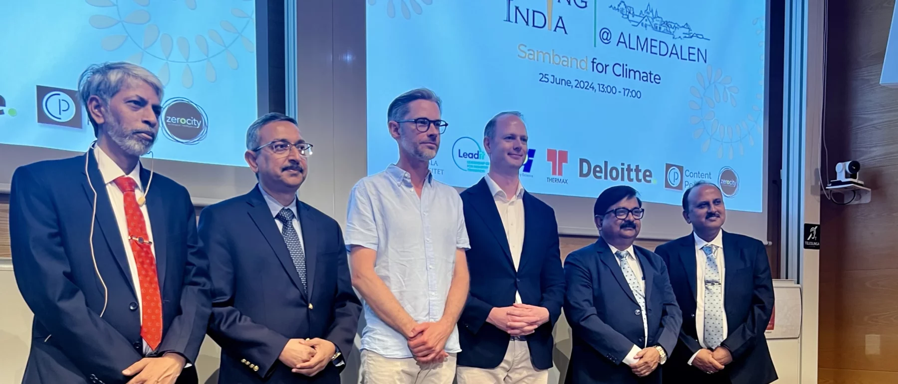 Group photo of six men on stage at the ‘Engaging India at Almedalen’ event, with logos of sponsoring organizations displayed on the screen behind them. The individuals, including the Indian Ambassador to Sweden and executives from SAIL and Cemvision, are dressed in business attire.