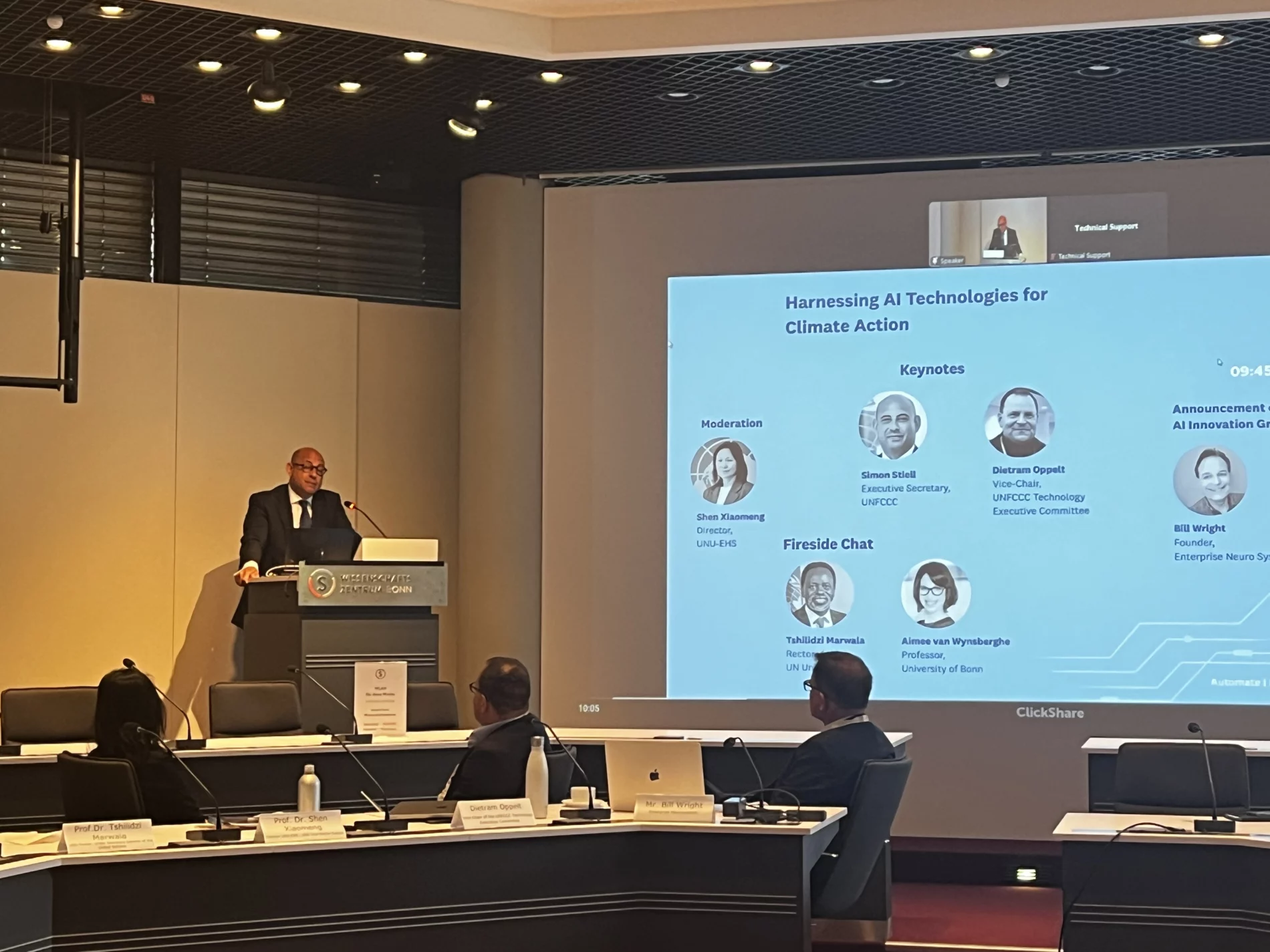 UNFCCC Executive Secretary Simon Stiell speaking at the AI & Climate Expert meeting in Bonn on July 1, with a presentation screen displaying information about the event and participants.