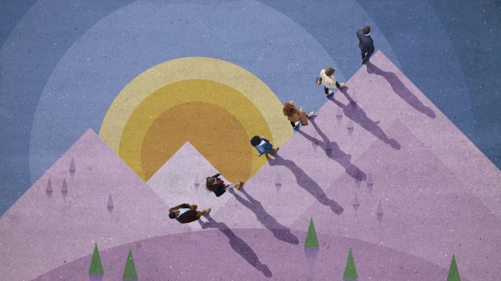 A top-down view of several people walking together up a colorful, abstract mountain landscape with overlapping geometric shapes, including a large sun and mountain peaks, under a gradient sky.