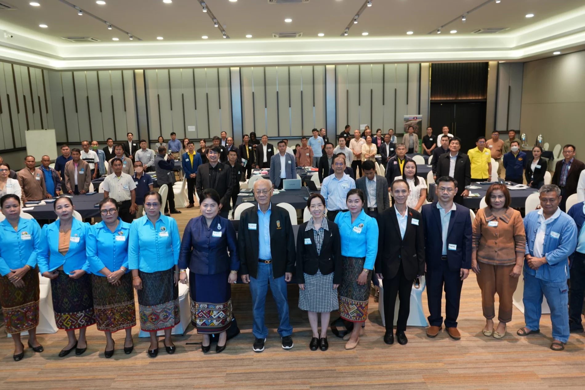 A large group of participants from Thailand and Laos pose for a group photo during the kick-off meeting of the SOS project. The attendees, dressed in formal and semi-formal attire, are gathered in a conference room, ready to share and discuss future risks and strategies to address them.