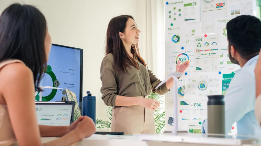 A group of adults in a meeting room looking at a board with information about environmental and social responsibility plans.