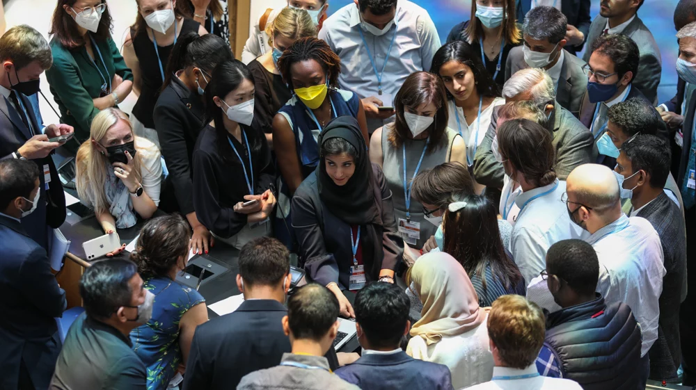 Delegates huddle during the contact group on the Global Stocktake, with a circle of people surrounding a woman in the middle looking up. 15 June 2022