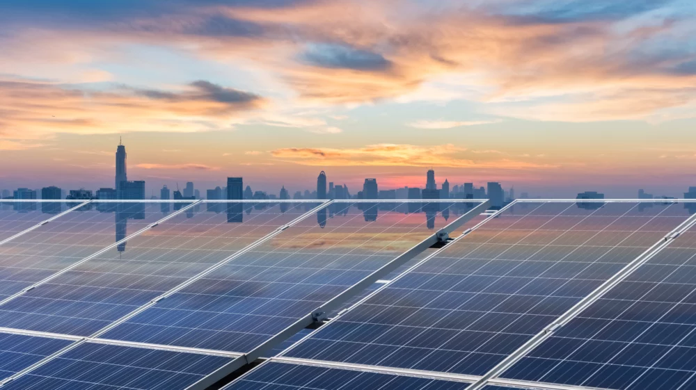 Solar panels with a city skyline in the background at sunset, symbolizing the shift to renewable energy in urban Southeast Asia.