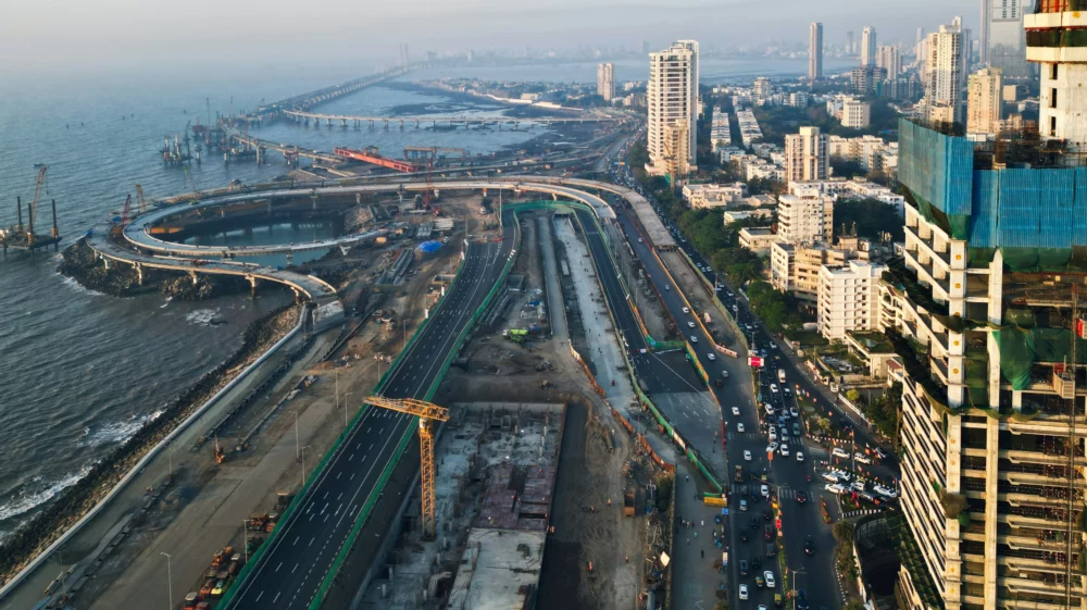 An aerial view of the construction of a coastal road being built next to a a row of high rise buildings in Mumbai, India