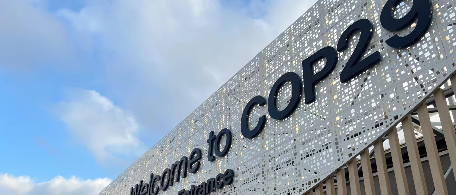 Entrance to COP29 conference with blue sky with white clouds in the background.
