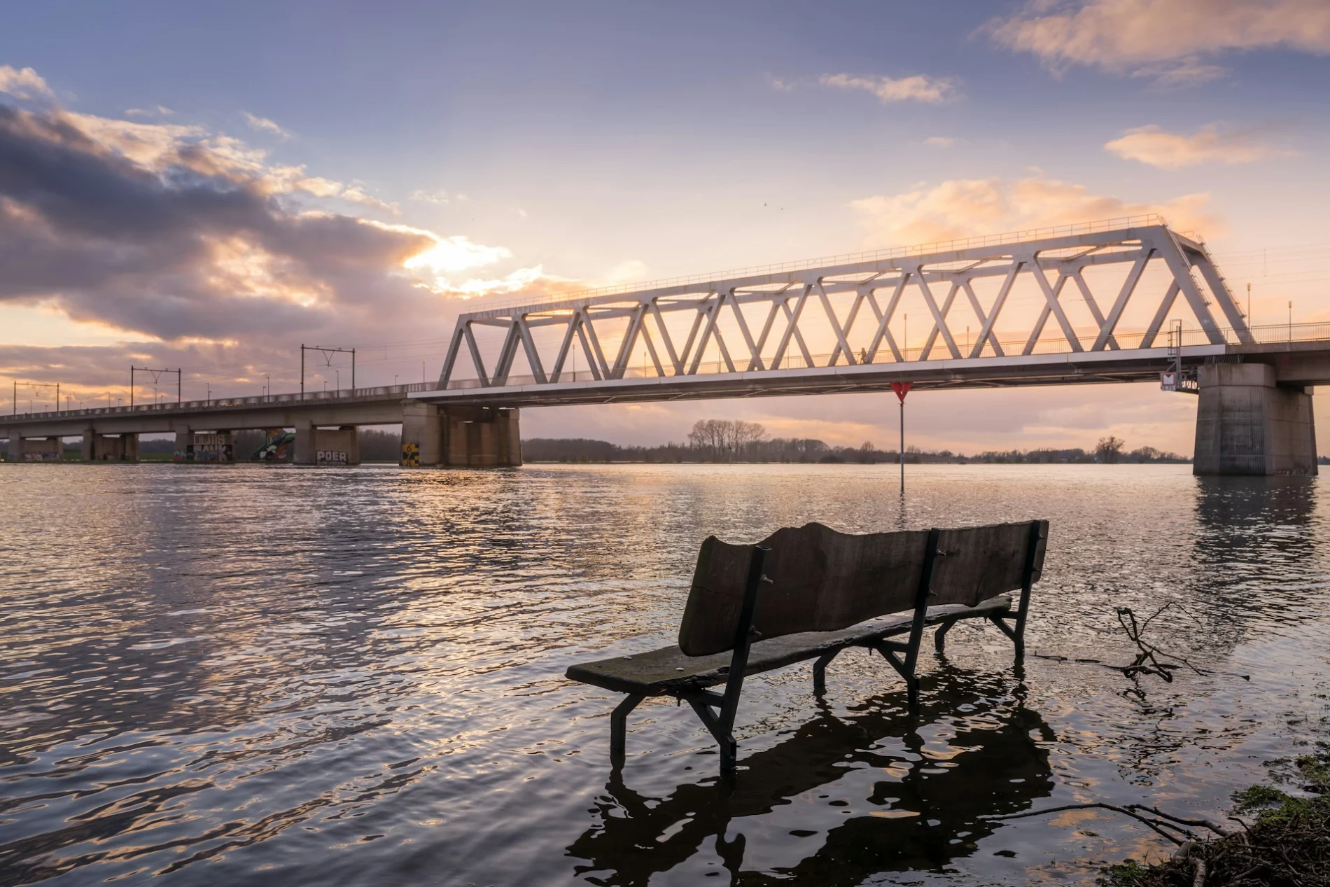Bench in water with bridge in the background in Deventer