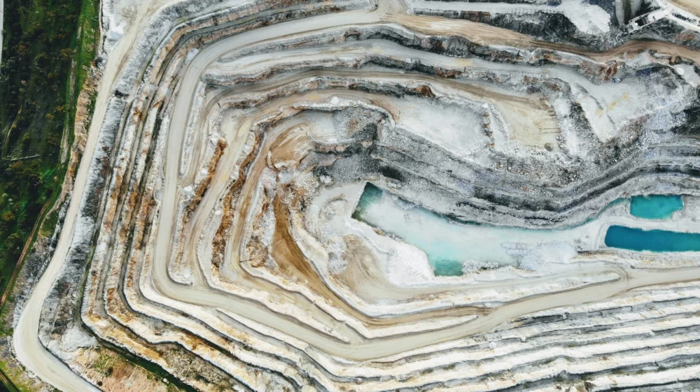 an aerial view of a white grey quarry with a blue pool in the middle