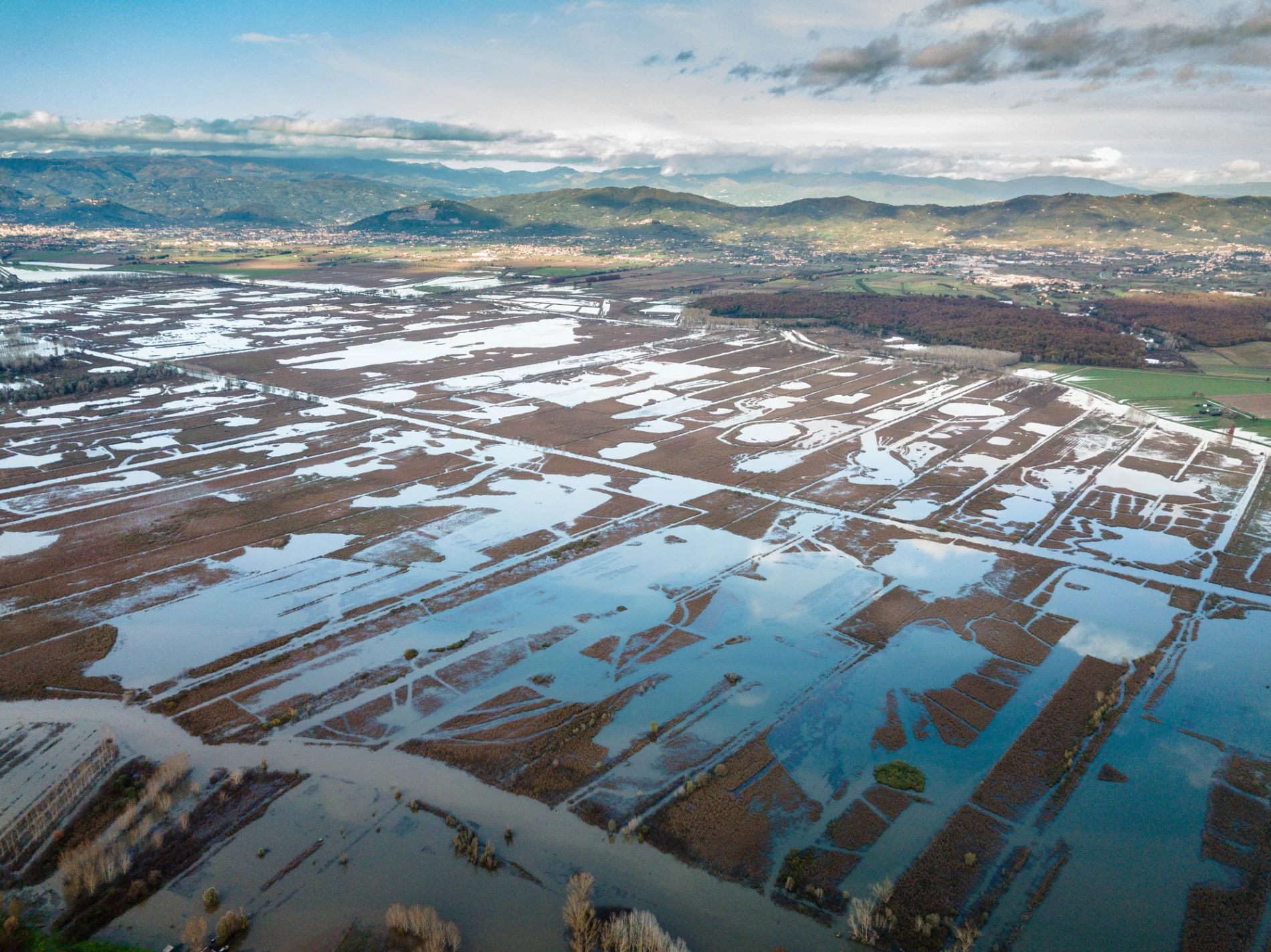 flooded fields from above with green mountains in the distance