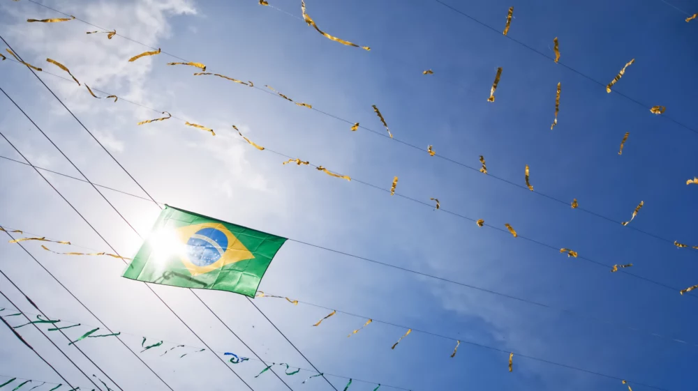 brazilian flag against cloud filled blue sky with streamers. horizontal wide angle composition looking up taken in buzios, rio de janeiro, brazil