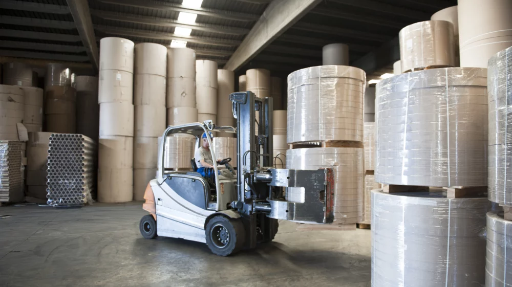 A forklift truck navigates towers of enormous reams of paper