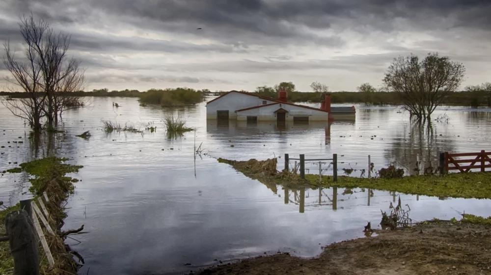 Aerial view of a flooded farmhouse under gray skies in Argentina