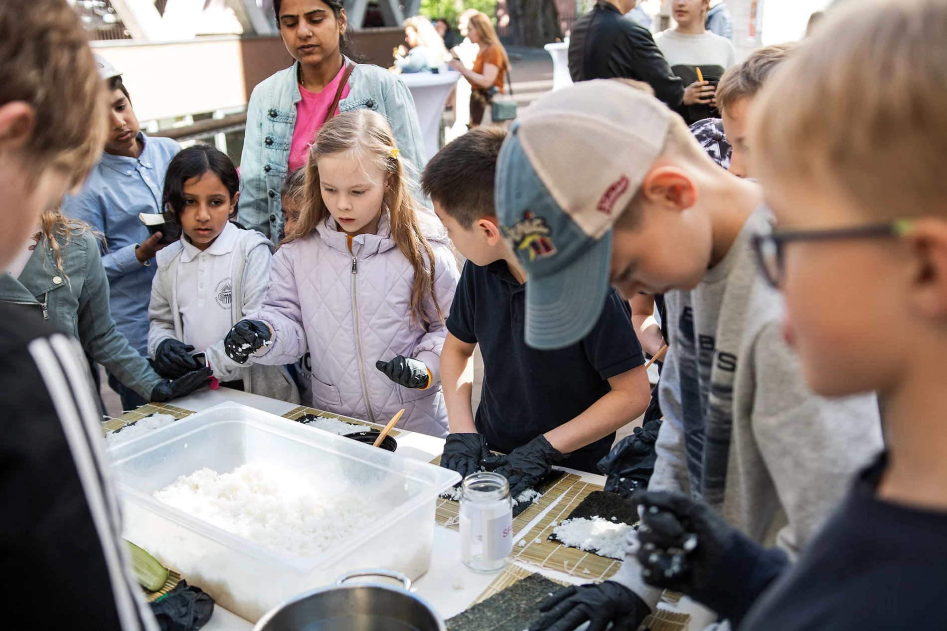 A group of children gathered around a table, participating in a hands-on activity involving rice and other materials.
