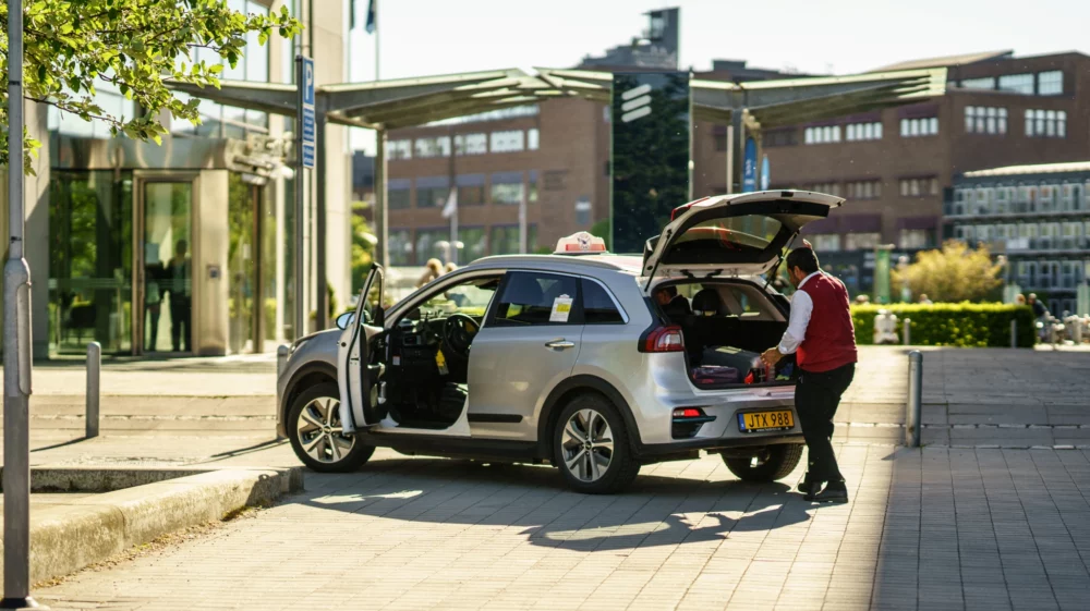 Electic taxi driver placing luggages in kia electric car