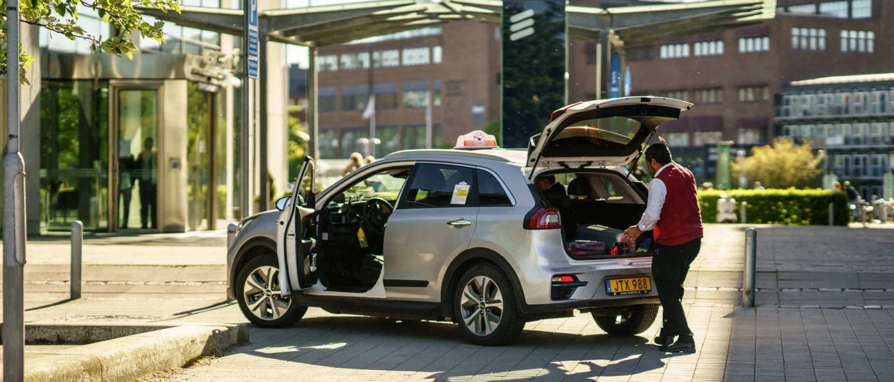Electic taxi driver placing luggages in kia electric car