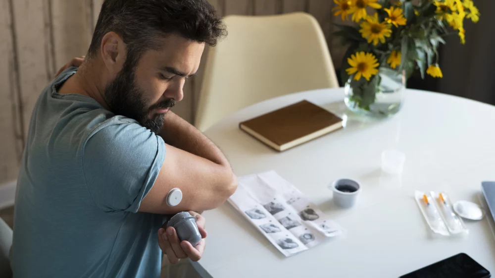 Diabetic man checking glucose patch sensor