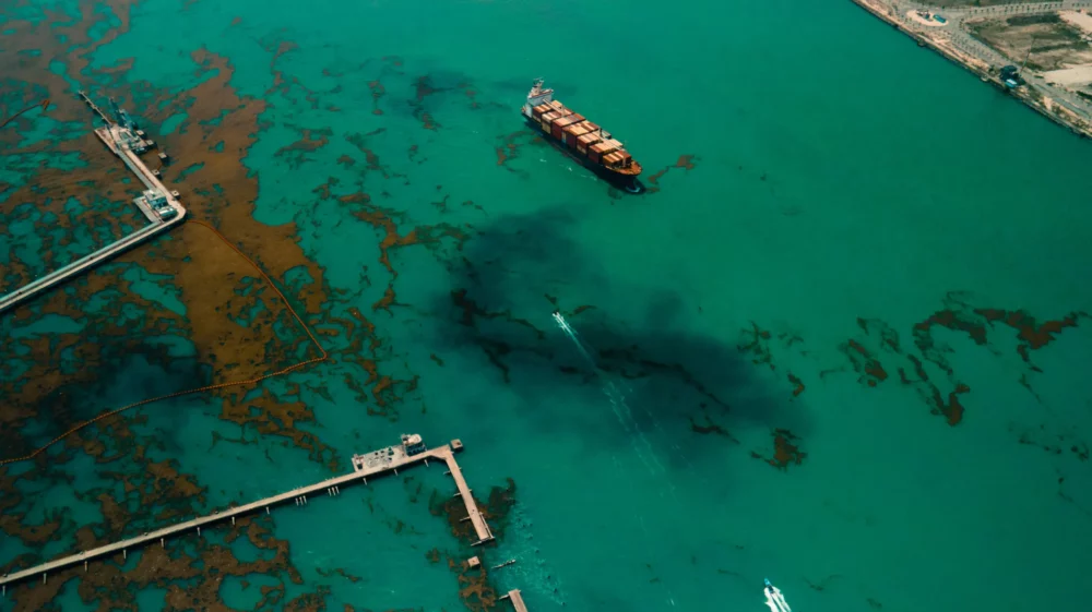 A container ship on the Atlantic ocean. An oil spill and algae formation is seen all over the path of the ship as it was travelling beside an oil depot in Lagos Nigeria.