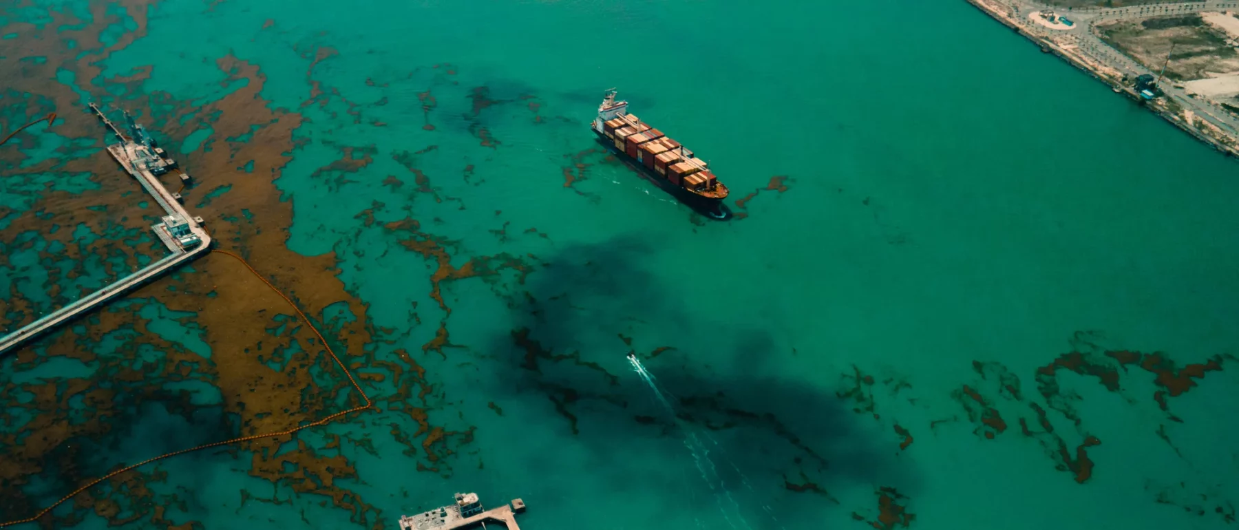 A container ship on the Atlantic ocean. An oil spill and algae formation is seen all over the path of the ship as it was travelling beside an oil depot in Lagos Nigeria.