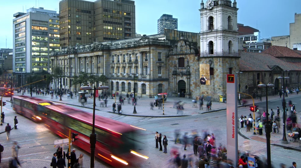 Busy traffic in Bogota, Colombia with red buses and many pedestrians
