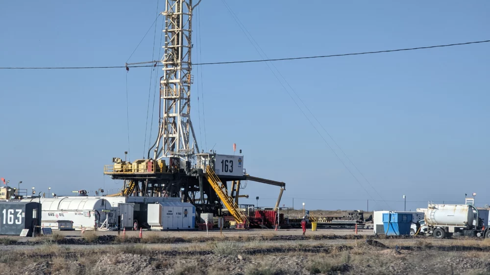 Fracking well towering over the landscape beneath blue sky in Vaca Muerta region of Argentina