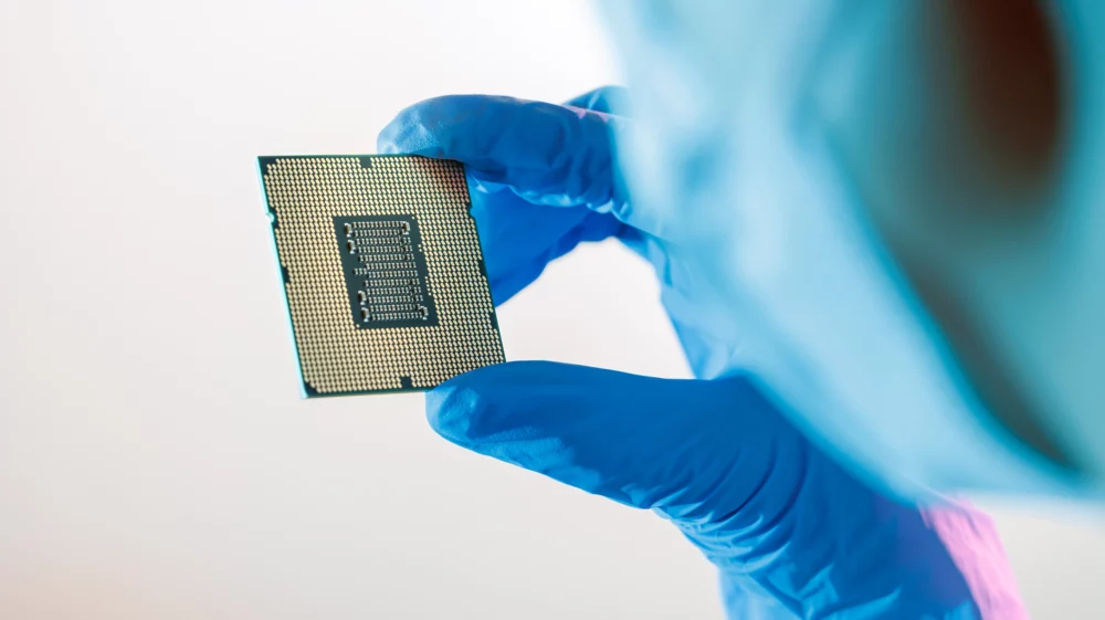 Close-up shot of a female Chinese factory worker wearing a mask and holding a CPU microchip and examining it.