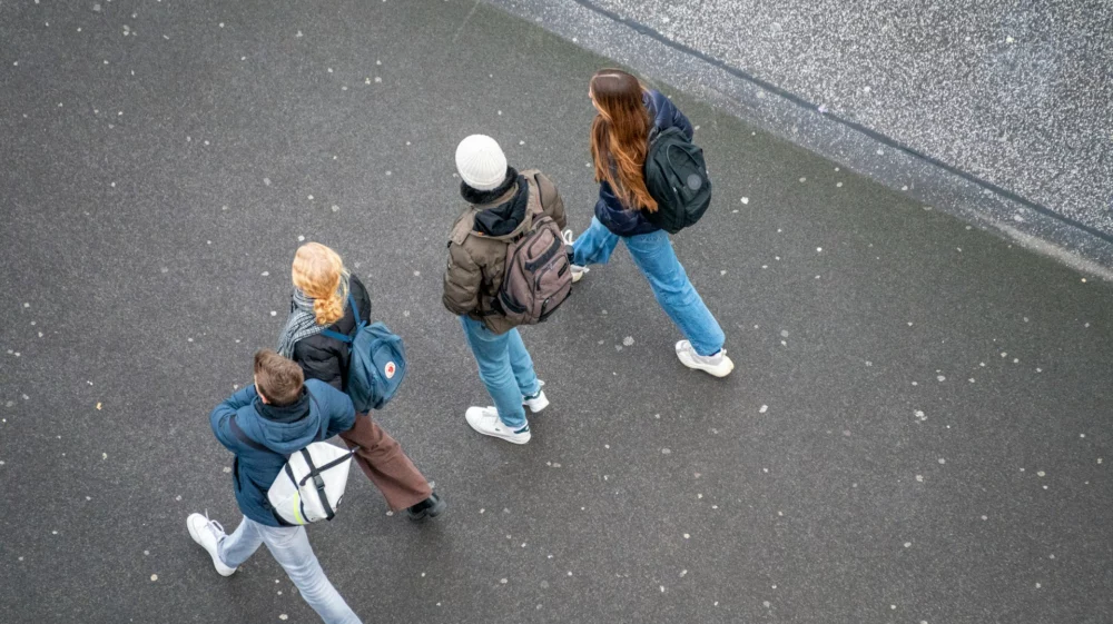 Aerial shot of four young people walking down a concrete street.