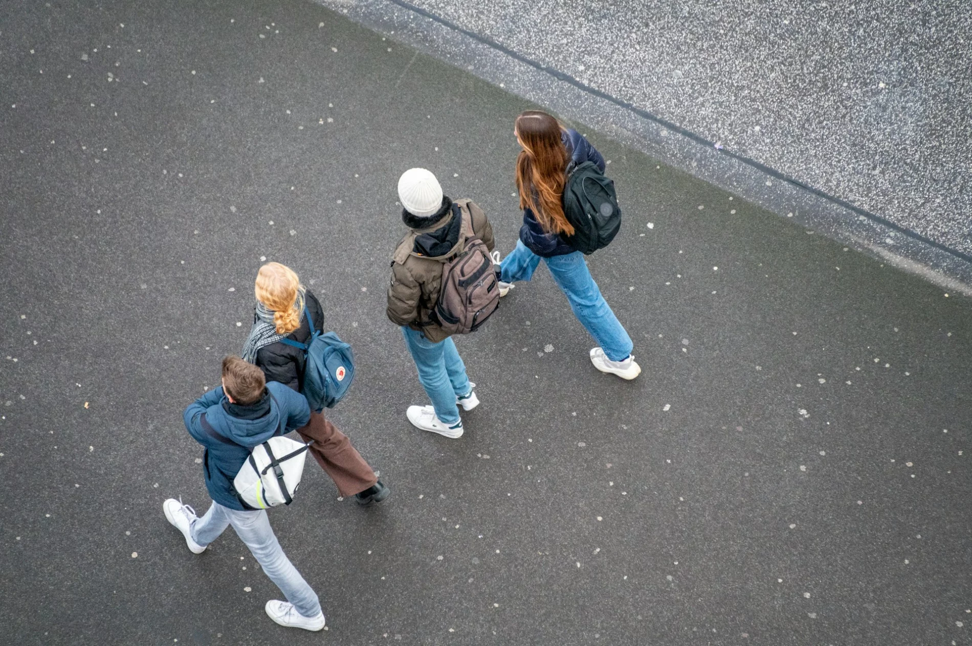 Aerial shot of four young people walking down a concrete street.