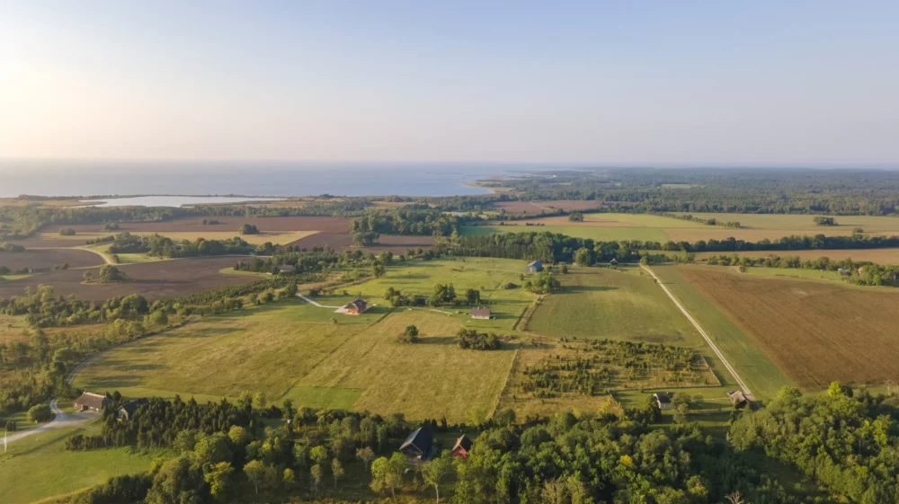 A stunning aerial view of Saaremaa’s vast rural landscape, showcasing the patchwork of fields, winding roads, and scattered farmhouses. The lush greenery and wide open spaces offer a serene and expansive perspective of Estonia's countryside. Saaremaa, Estonia, August 2024