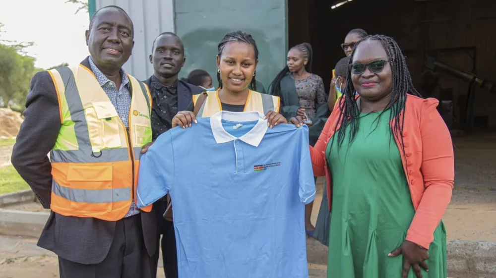 Three people holding a shirt at the centre