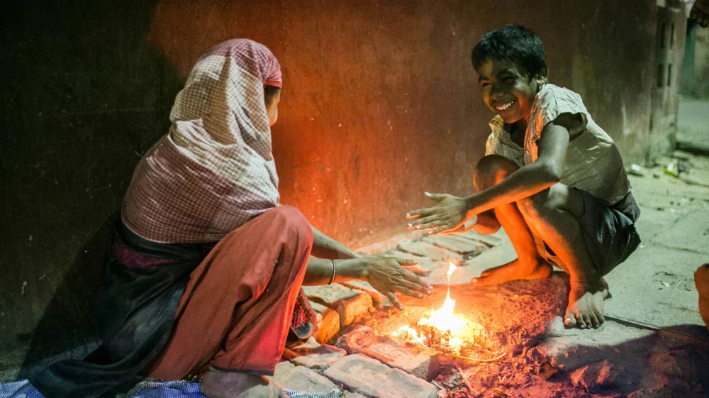 An indian woman and child laughing around a fire in Kolkota, India