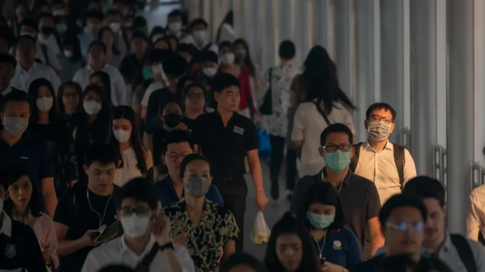 A crowd of early-morning commuters wearing face masks on their way to work in Bangkok.