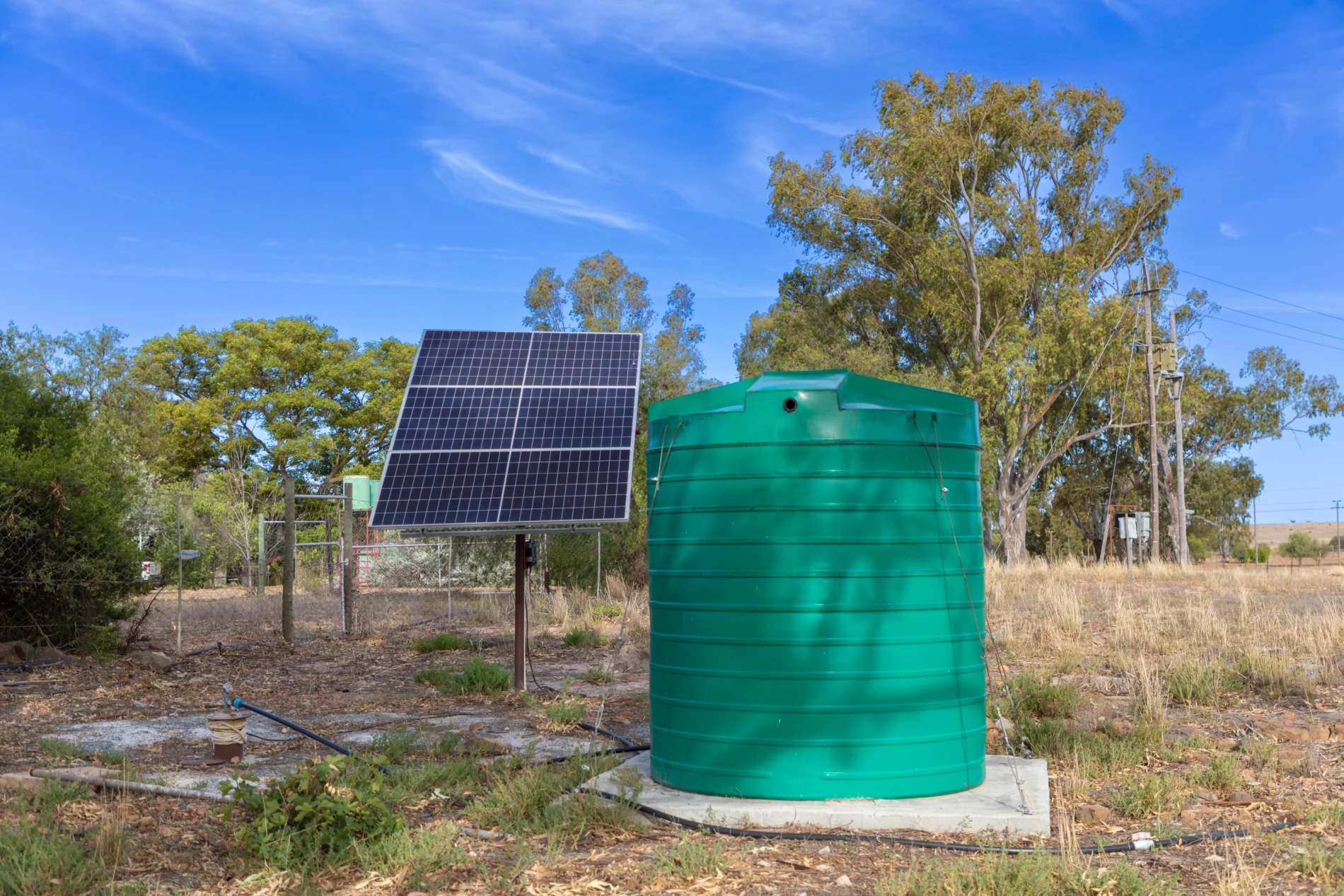 Large green plastic storage tank with solar panes connected to a borehole