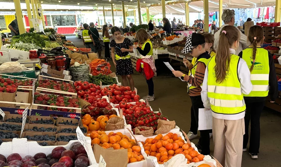 Kollaste vestidega lapsed turul, ümberringi puu- ja juurviljad.