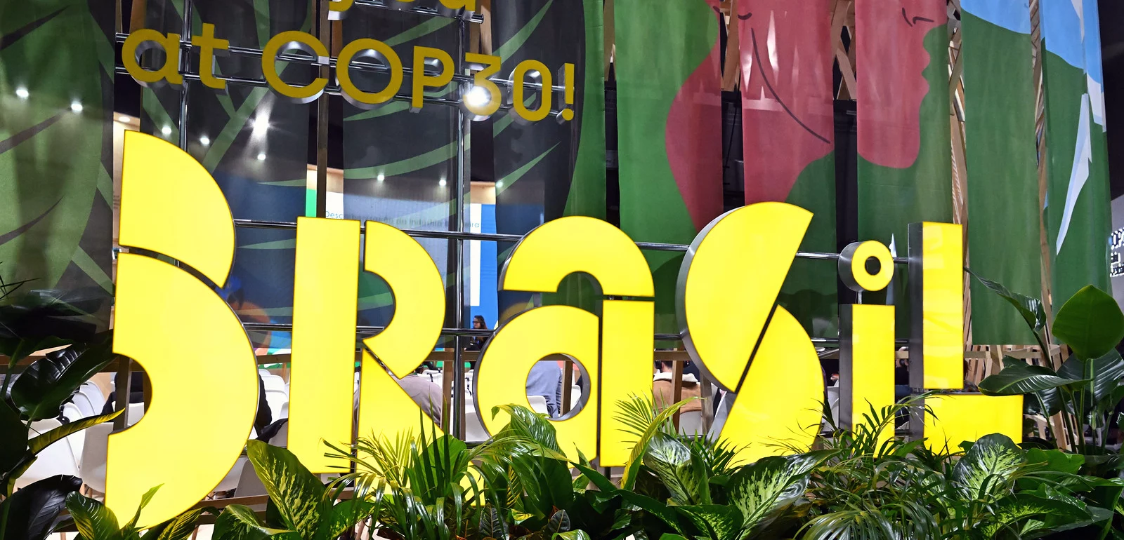 Large yellow “Brasil” sign surrounded by plants with “See you at COP30!” displayed in the background.