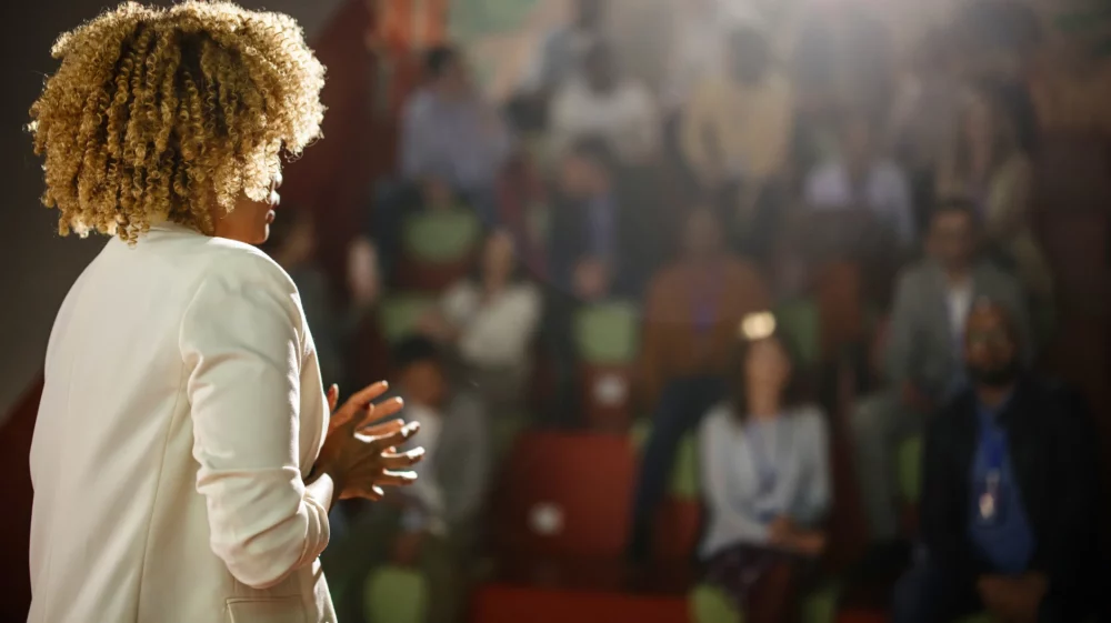 Rear view of a public speaker giving talk at conference event.