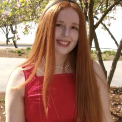 Photo of Samantha, with long red hair wearing a black headband and red dress