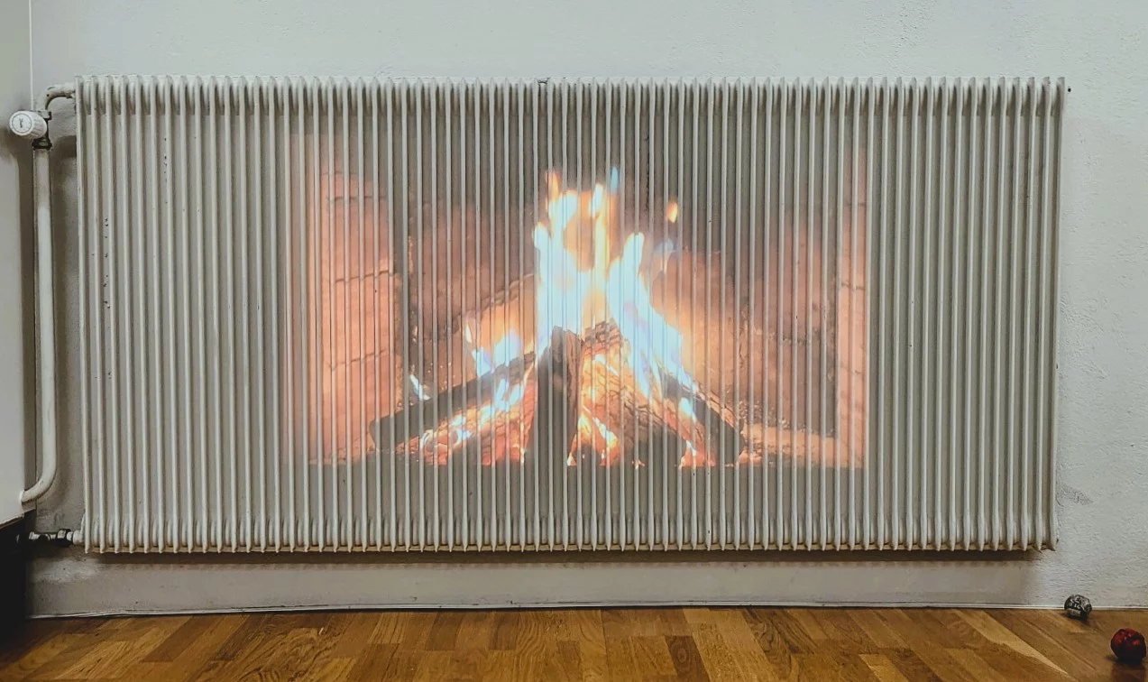 Projection of a fire onto a white radiator, symbolizing past and present experiences of energy poverty.
