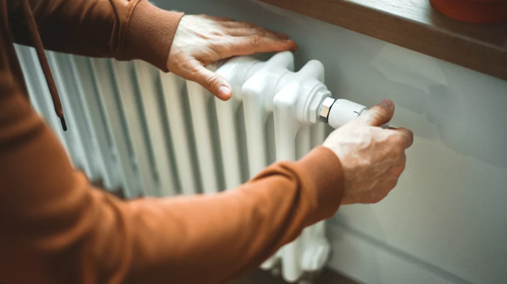 Man warms himself by the radiator