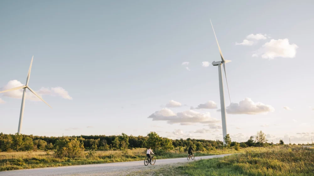 Cyclists riding near wind turbines on a sunny day in the countryside landscape