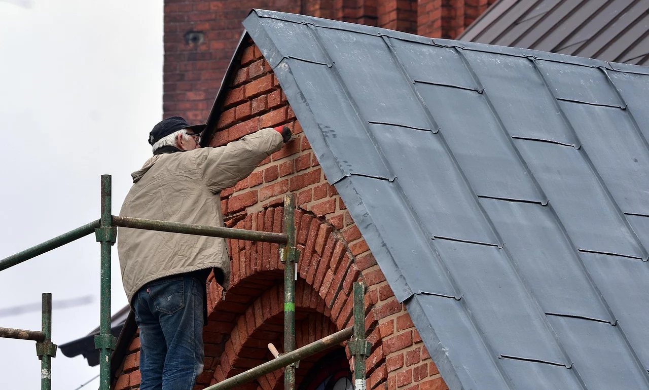 A man renovating the roof of a house standing on scaffolding.