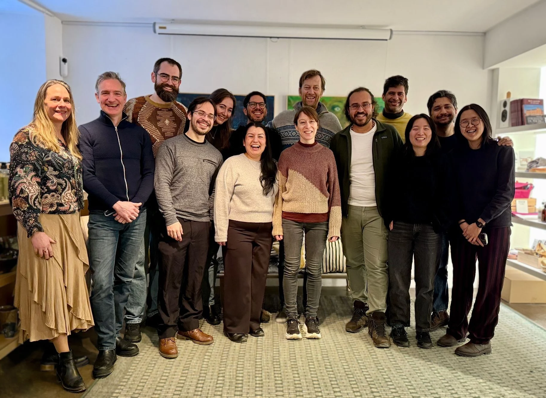 Fourteen members of the Trase team stand together indoors, smiling for a group photo in an office environment, with shelves in the background.