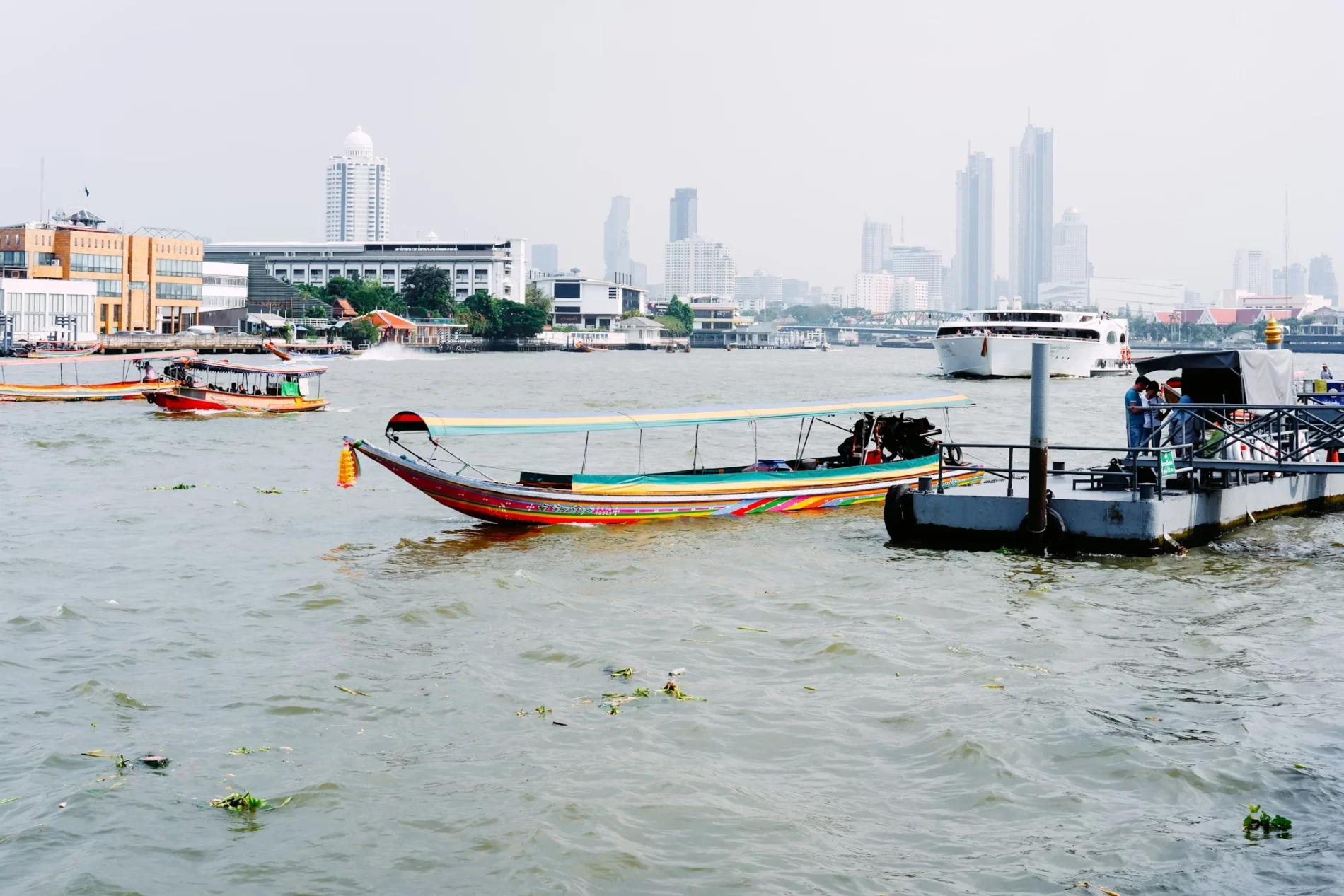 a group of boats floating in body of water with city landscape in the background