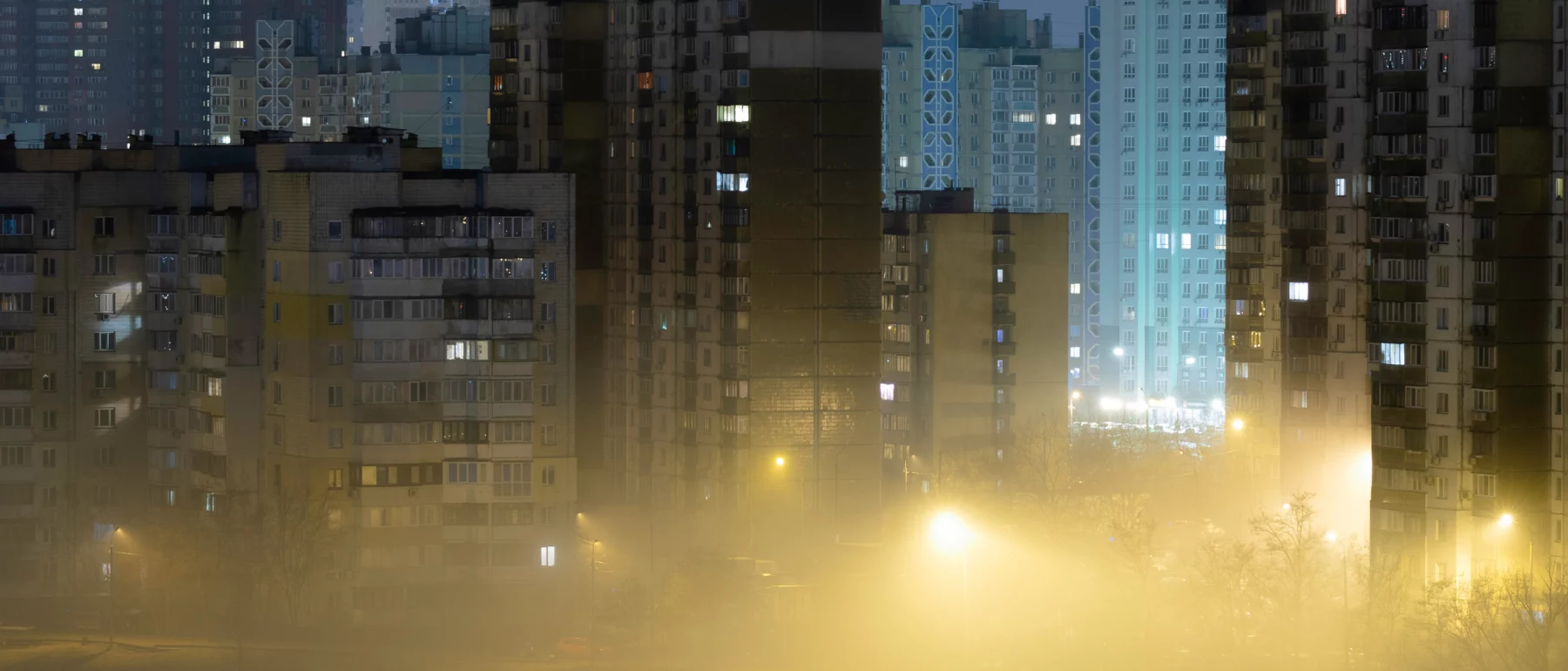 Night cityscape of the big city. Awesome bright, multi colored light in thick fog at empty streets. Apartment buildings in bedroom community, commuter town area.