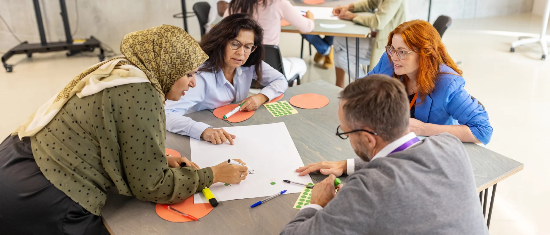 Diverse group of people working on an activity, using stationary and craft materials.