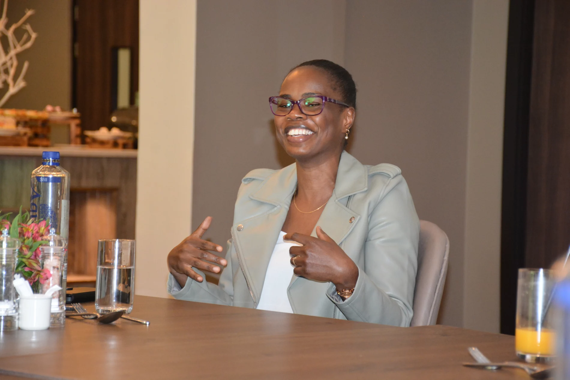 A woman wearing glasses smiles at a conference table
