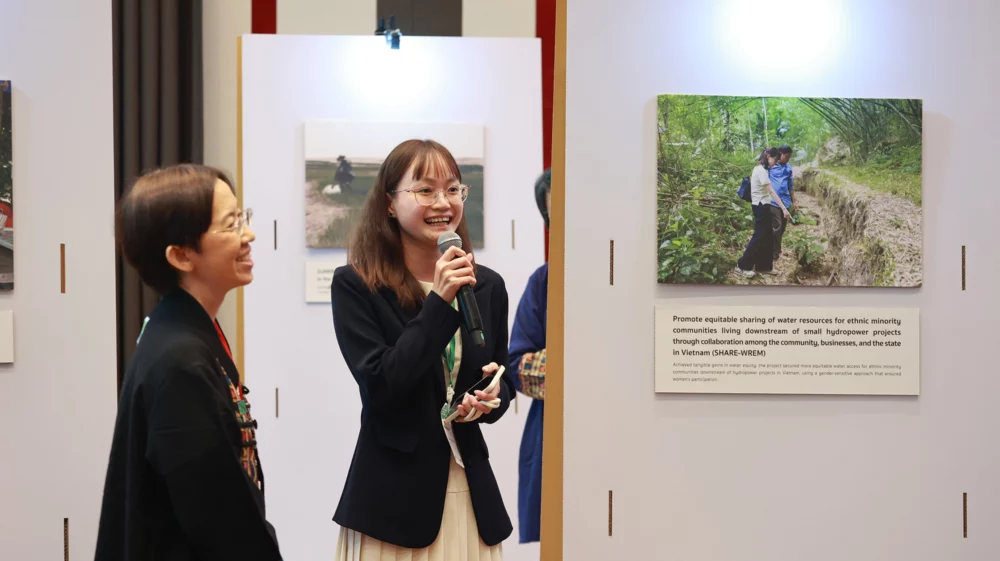 Person speaking into microphone in front of poster