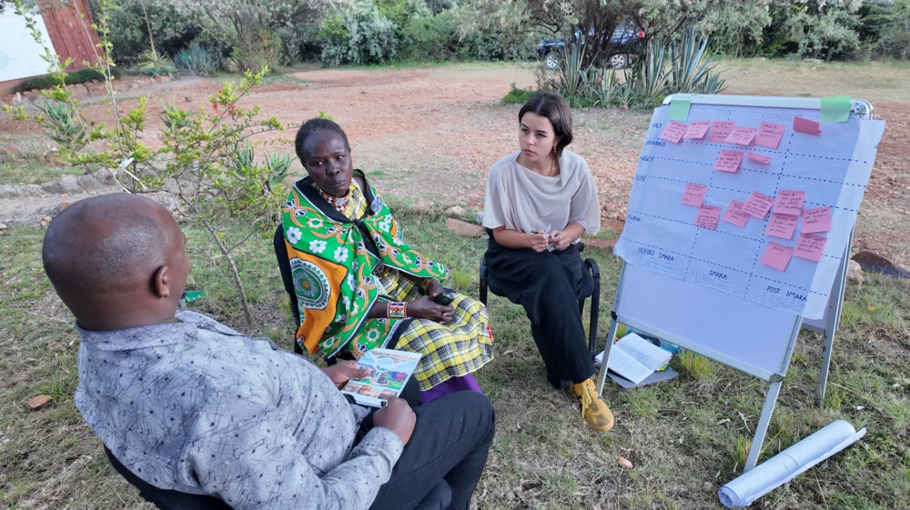 three people sit together outside in discussion
