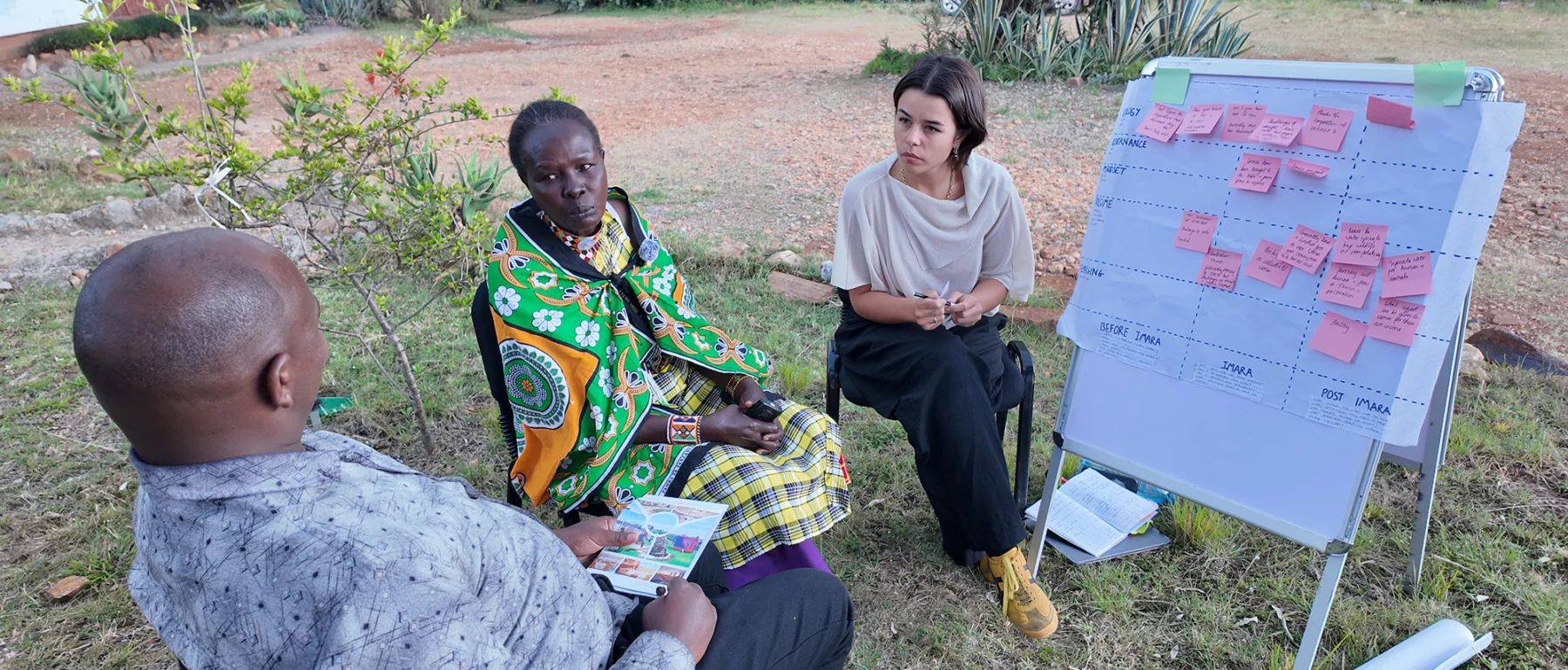 three people sit together outside in discussion